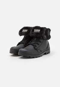Bottines noires avec une tige en cuir texturé, un col en fausse fourrure, un bout rond, un devant lacé et une semelle en caoutchouc robuste avec un motif de crampons.