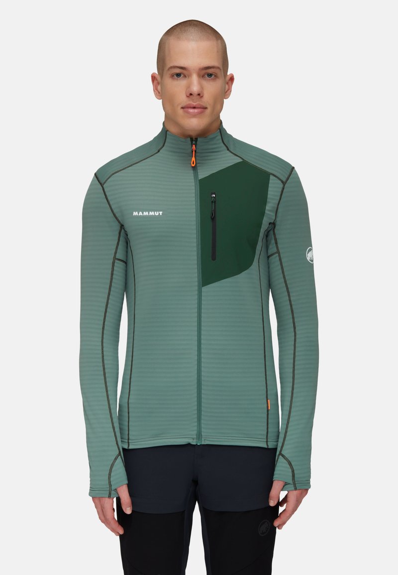 Groene ritsjack met horizontale strepen, voorzien van een donkergroen paneel, een ritszak en een oranje ritslip. Gladde, atletische uitstraling.