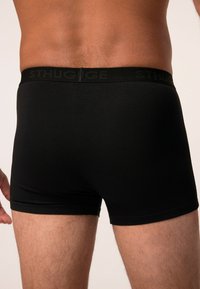 Boxers negros hechos de una tela suave, con una cintura elástica que presenta un discreto detalle de logo. El ajuste se adapta a los muslos y la cintura.