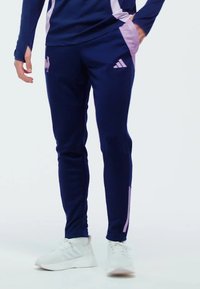 Pantalons de sport navy avec des accents violets. Fabriqués en tissu léger, dotés d'une coupe fuselée et de bandes latérales, conçus pour le confort et le mouvement.
