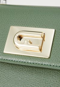Sac à main en cuir texturé vert avec un fermoir rectangulaire doré au design de boucle distinctif.