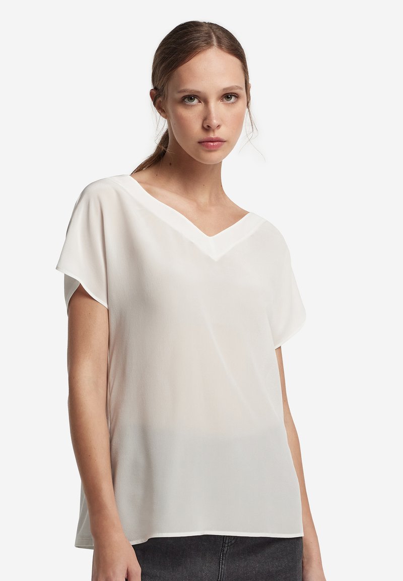 Blouse blanche légère et transparente avec un col en V, des manches courtes, une coupe décontractée, réalisée dans un tissu lisse avec un tombé subtil.