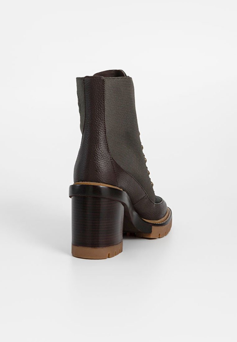 Brązowe skórzane botki za kostkę z teksturowanym zielonym panelem bocznym, masywnym brązowym obcasem i okrągłym noskiem. Widoczne wzmocnione szwy.