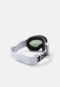 Las gafas cuentan con una tira elástica blanca con un logo negro, un acolchado suave negro y lentes tintados con un diseño redondeado.