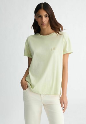 Light green short-sleeve t-shirt made of soft fabric with a round neck and a small, beige logo on the chest. Minimalist design.