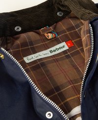 Casaco azul marinho com colarinho em sarja. O forro interno apresenta um padrão xadrez em tons de castanho. As etiquetas dizem "Paul Smith ama Barbour." Zíper prateado.