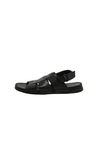 Sandalo in pelle nera con un design a strisce, punta aperta, fascetta alla caviglia regolabile e dettagli testurizzati sulla parte superiore. Sole piatto.