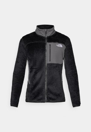 Black fleece jacket with a textured surface, gray panel at the chest, full zip, high collar, and logo on the upper left side.