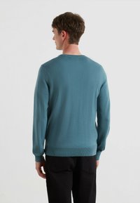 Sweter dziany w kolorze teal z długimi rękawami i ściętym dołem, posiadający klasyczny okrągły dekolt oraz fakturowany materiał.