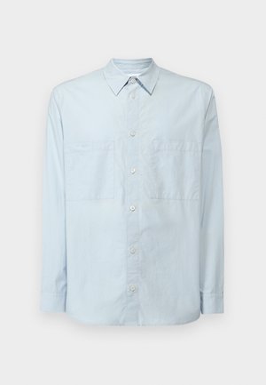 Camisa abotonada de color azul claro hecha de algodón, con un cuello clásico, mangas largas, dos bolsillos en el pecho y un ajuste ligeramente relajado.