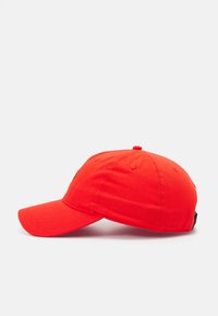 Red cotton baseball cap with a curved brim, six ventilation holes, and an adjustable strap at the back. Features a logo on the front.