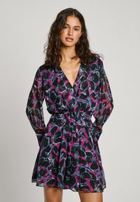 Robe transparente à motif floral en noir avec des accents rose, violet et bleu. Présente des manches longues, un décolleté en V et une taille cintrée.