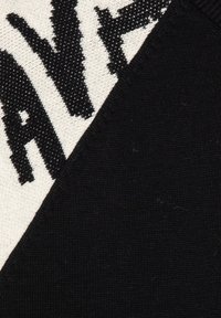 Schwarzer und cremefarbiger Stoff mit auffälligem, gedrucktem schwarzen Text auf einem strukturierten Hintergrund. Das Design kombiniert kontrastierende Farben und Muster.