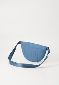 Borsa a tracolla blu trapuntata a forma di mezza luna, con una texture liscia, tracolla regolabile e chiusura con zip.