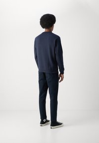 Marineblauwe sweatshirt met lange mouwen, ribbelmanchetten en onderkant. Gecombineerd met bijpassende marineblauwe broek en zwarte hoge sneakers. Minimalistisch ontwerp.