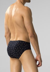 Granatowe kąpielówki z wzorem z małymi, powtarzającymi się złotymi akcentami. Wykonane z gładkiego, elastycznego materiału.