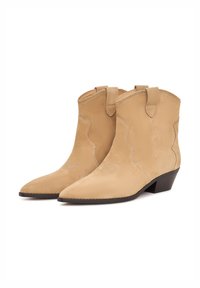 Botine din nubuc de culoare bej, cu vârful ascuțit, cusături decorative și mânere de tragere. Toc mic tip bloc și textură netedă. Design western elegant.