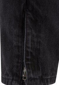 Black denim pants featuring a side zip pocket and a textured fabric. The stitching is visible, adding detail to the garment's structure.