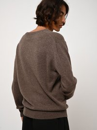Maglione marrone a maglia testurizzata con scollatura tonda e spalle drop. Il tessuto appare morbido e leggermente aderente in vita.