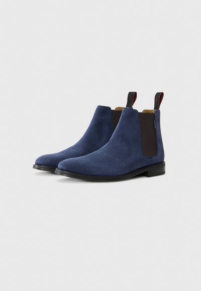 Bottes Chelsea en daim bleu marine avec des panneaux latéraux élastiques, un bout rond et une petite languette à l'arrière. Semelle en caoutchouc noir.