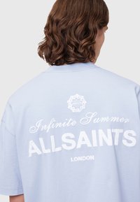 Gaiši zils pārspīlēts T-krekls ar baltu tekstu: "Beidzamā vasara" un "ALLSAINTS LONDON", ar apļa logotipu virs teksta.