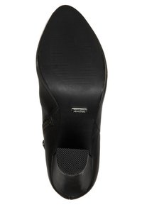 Svart högklackad sko med en slät läderövre, spetsig tå och texturerad innersula; har en elegant, minimalistisk design.