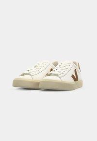 Sneakers bianchi con accenti in suede marrone, punta tonda, suola piatta in gomma e chiusura con lacci. Realizzati in materiale liscio con design minimalista.
