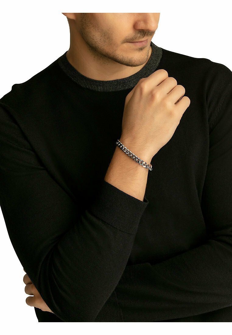 Bracciale in acciaio inox argento indossato a un polso, caratterizzato da grandi anelli intrecciati con una finitura lucida. Adatto per l'uso quotidiano.