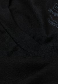 Schwarzer Baumwollstoff mit einer weichen, glatten Textur. Verfügt über einen runden Halsausschnitt und sichtbare Nähte, sieht leicht zerknittert aus.