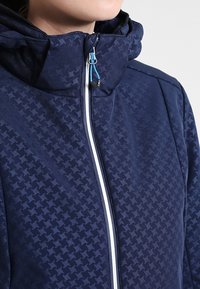 Marineblaues Kapuzenjacke mit einem subtilen Hahnentrittmuster, strukturiertem Stoff, Frontreißverschluss mit weißem Besatz und blauen Akzenten.