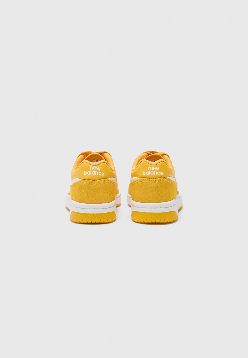 Sneakers in camoscio giallo con dettagli bianchi. Presentano una forma arrotondata e una suola imbottita. Logo del marchio visibile sul tallone.