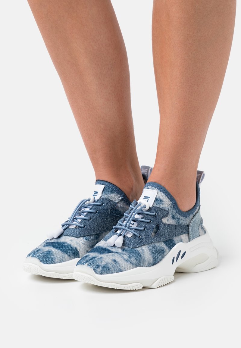 Chaussures de sport bleues à motifs avec une tige en tissu texturé et une semelle blanche légère. Les lacets avec attaches permettent un ajustement personnalisé.