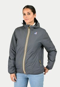 Grijze hoodie jack van lichtgewicht materiaal met gele en witte ritsen, elastische manchetten en zijzakken. Logo patch op de borst.