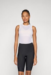 Hvit mesh ermeløs topp kombinert med svarte sykkelshorts, med en kroppsnær fasong og sømdetaljer for forbedret støtte.