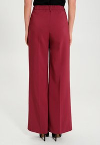 Vida jeans i burgunderröd tyg med elastisk midja, med en slät textur och hel-längd skärning.