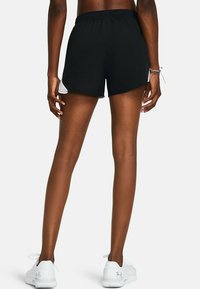 Svarta sportshorts med elastisk midja och lös passform, med sidopaneler i mesh. Matchas med vita sportskor.