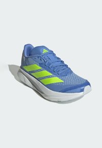 Blauwe sportschoen met een bovenwerk van mesh, groene accentstrepen en een witte zool. Bevat een gevoerde tong en gestructureerde detailing op het bovenwerk.