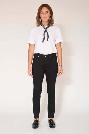 T-shirt blanc à manches retroussées, jean skinny noir taille haute et mocassins noirs. Accessoirisé d'une écharpe noire à motif.