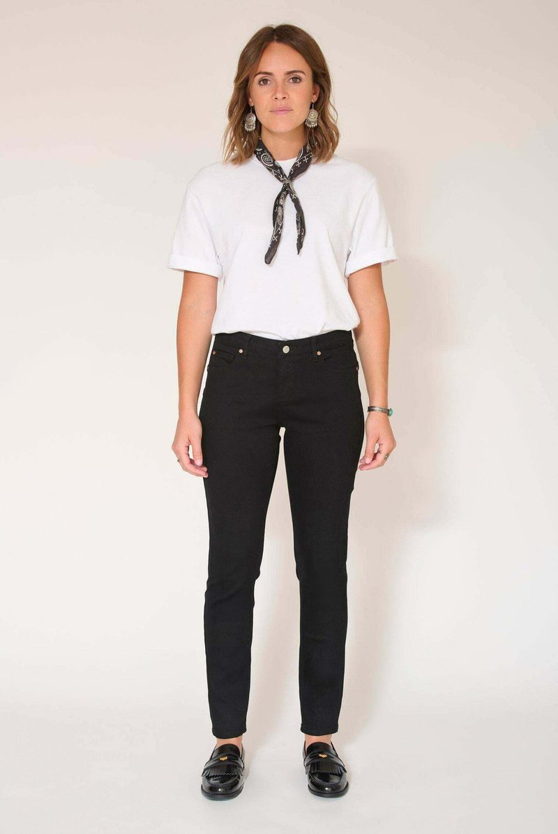T-shirt blanc à manches retroussées, jean skinny noir taille haute et mocassins noirs. Accessoirisé d'une écharpe noire à motif.