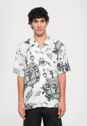 Chemise à manches courtes blanche avec des imprimés détaillés en noir de cages à oiseaux, de fleurs et d'insectes, comprenant un col et une fermeture à boutons.