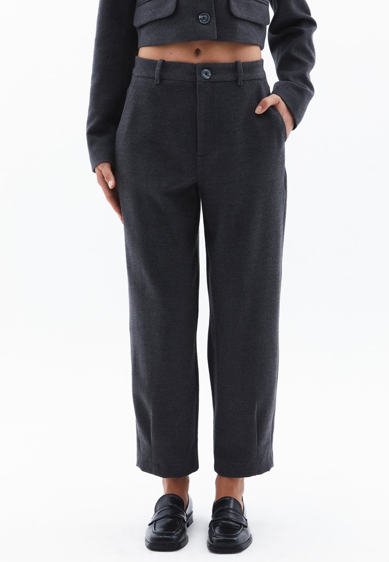 Donkergrijze op maat gemaakte broek met een rechte pasvorm, voorzien van riemlussen, zijzakken en een knoopsluiting. Fluftige wolmix stof.