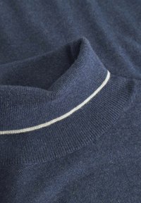 Maglione lavorato a maglia blu navy con colletto alto e dettaglio a striscia bianca, di texture morbida e design rilassato e drappeggiato.