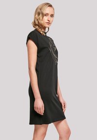 Schwarzes Kurzarmkleid mit einer lockeren Passform, das ein grafisches Design auf der Vorderseite aufweist. Weicher Stoff und glatte Textur.