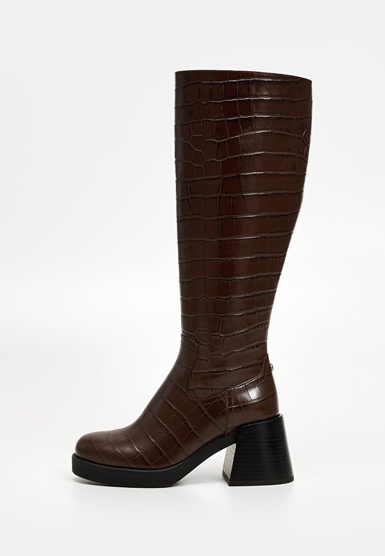 Stivale al ginocchio marrone con embossing a coccodrillo, dotato di un tacco largo e una finitura lucida e texturizzata. Presenta una punta rotonda e una fodera interna liscia.