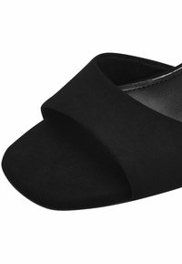 Sorte ruskinds slidesandaler med en bred strop og åben tå-design. Struktureret overflade med en glat inderside for komfort.