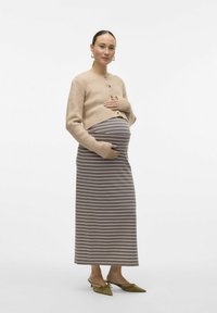 Gebreide beige cardigan met geribbeld textuur en knopen; grijs-wit gestreepte maxi-jurk; olijfgroene puntige schoenen met strikaccent.