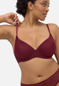 Sujeción con encaje burdeos y patrón geométrico texturizado. Cuenta con tirantes ajustables y aros para mayor soporte.