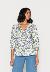Blusa floral branca com flores azuis e folhas verdes, decote em V, mangas três quartos e design de cintura peplum. Material em algodão.