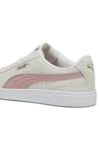 Weiße Wildledersneaker mit pinkem Seitenstreifen, goldenem Logo und weißer Gummisohle. Strukturierte Oberseite und gepolsterter Kragen für zusätzlichen Komfort.