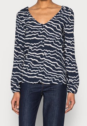 Navy blouse met een wit golfpatroon, v-hals, lange pofmouwen en een knopenlijst. Gemaakt van lichtgewicht stof met een gladde textuur.